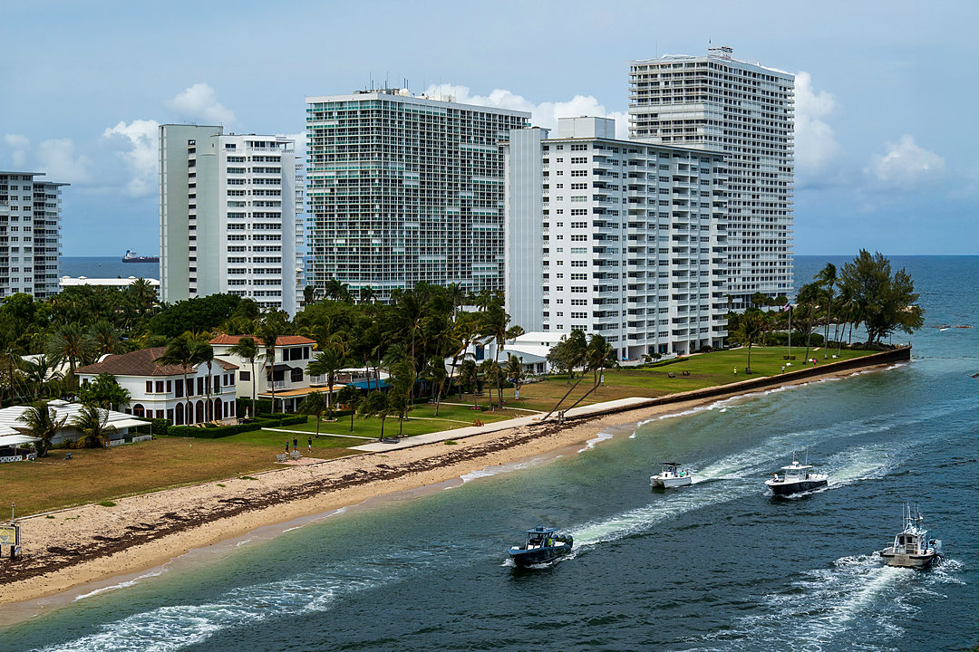 Aerial view of Fort Lauderdale beachfront high-rises and boats leaving the inlet